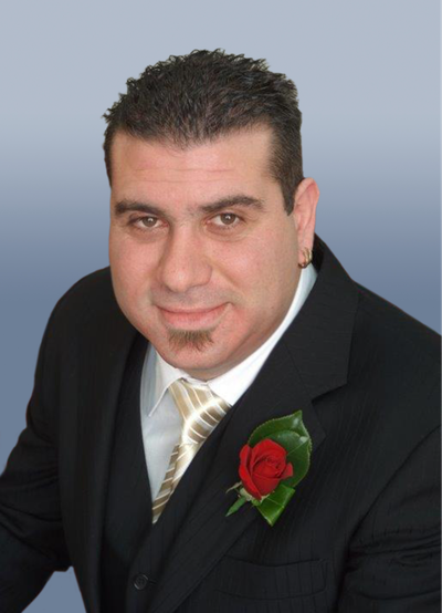 A man smiling in a suit with wedding flowers 