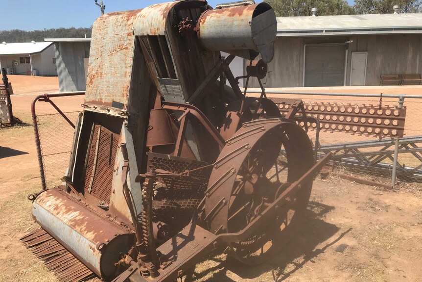A rusting Sunshine harvester sits in a paddock.