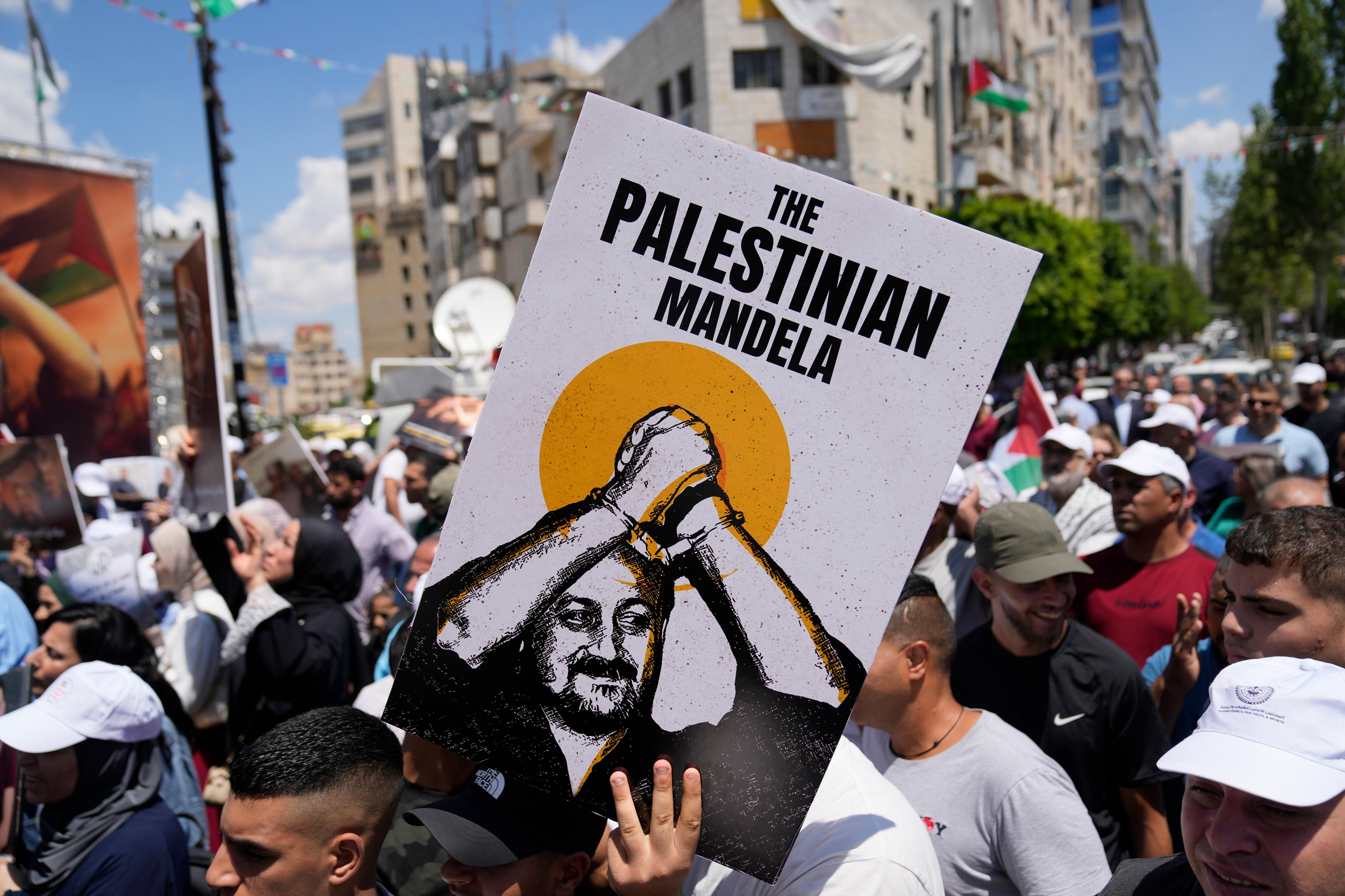 A man holds a sign of Marwan Barghouti with the words "The Palestinian Mandela" at a busy protest.