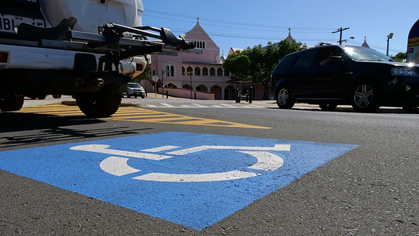 A blue-and-white disabled car parking bay with cars close by