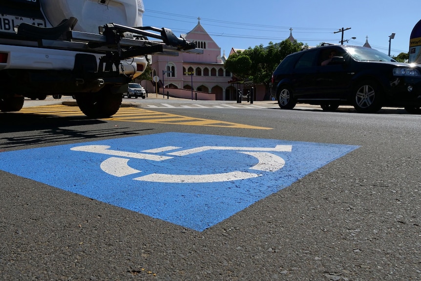 A blue-and-white disabled car parking bay with cars close by