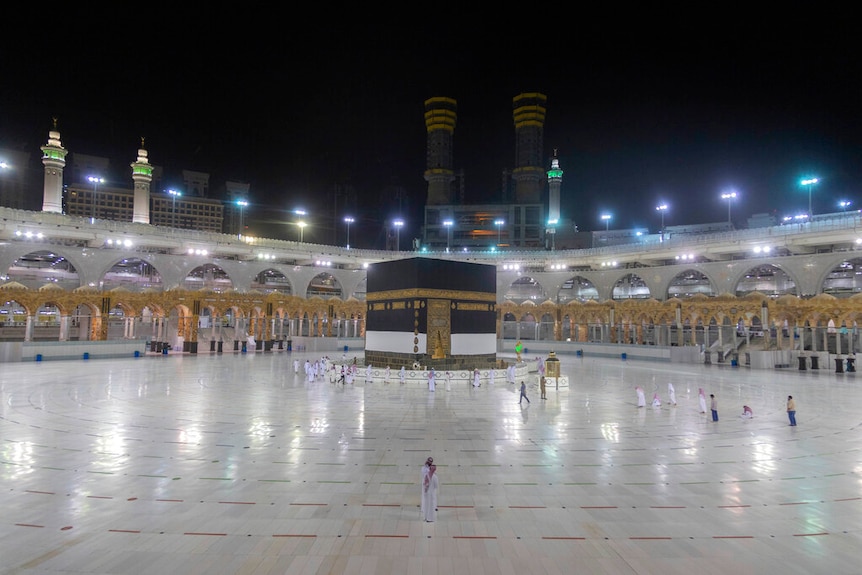 Pilgrims shown metres apart  in front of  the Kaaba, the sqaure draped in black and gold, during a night-time prayers.