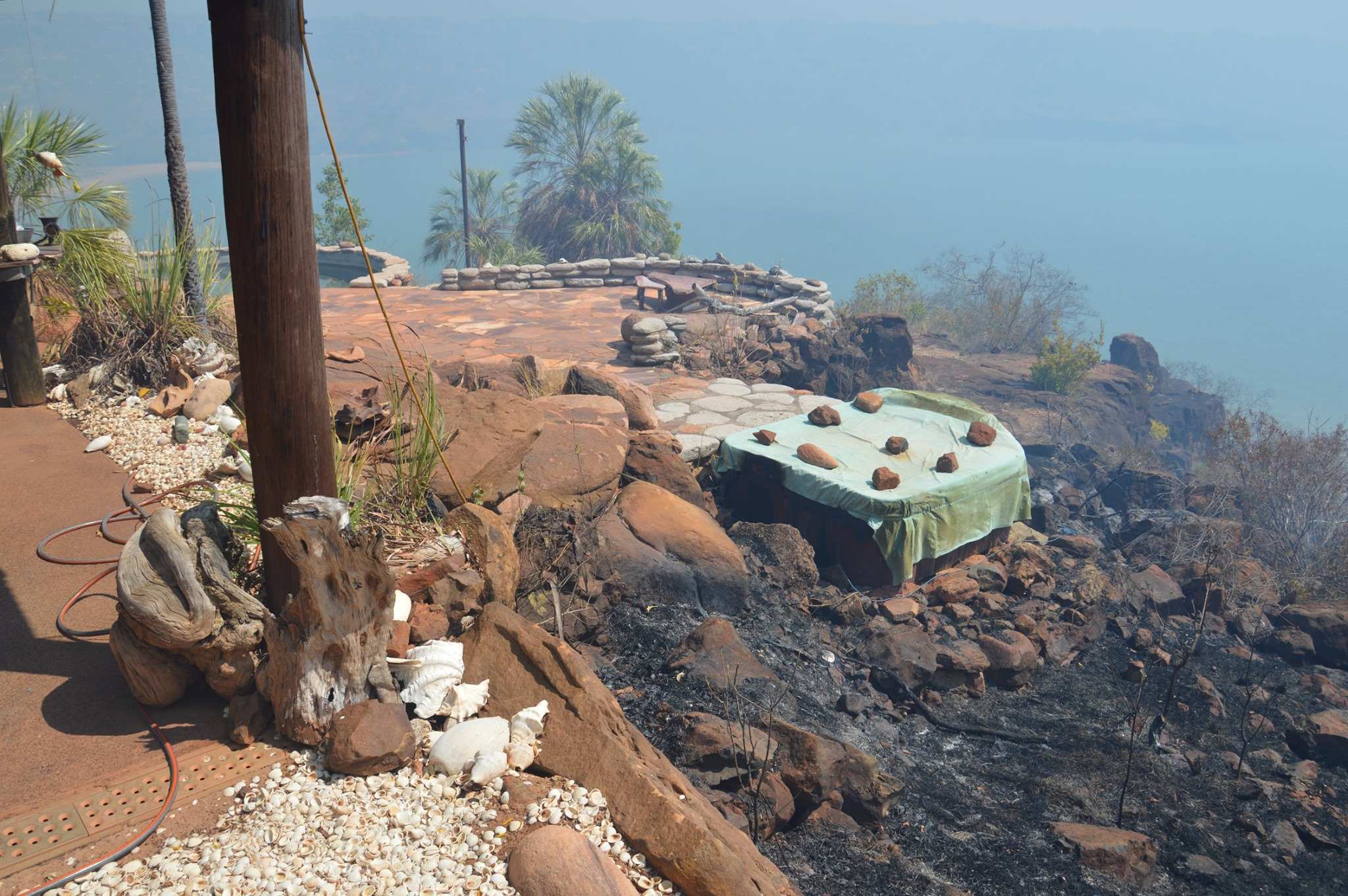 Image of a burned landscape stretching up to the side of a building in a remote part of the Kimberley.