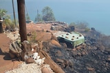 Image of a burned landscape stretching up to the side of a building in a remote part of the Kimberley.