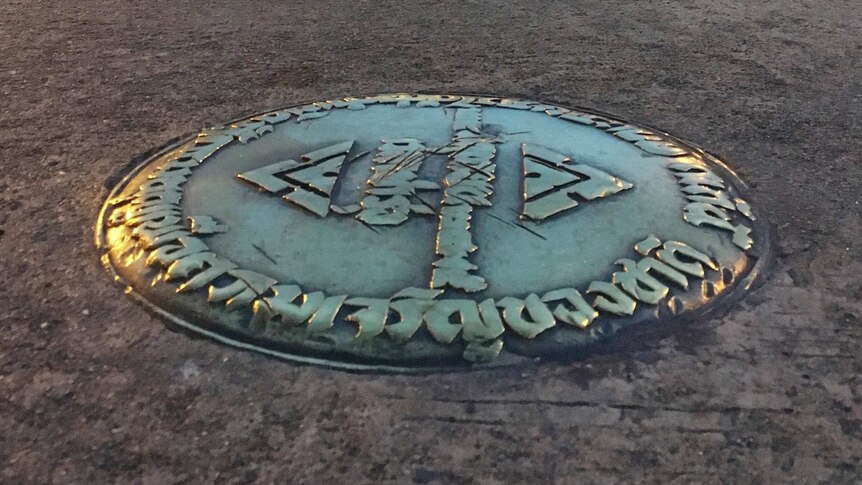 A round bronze plaque surrounded by cement