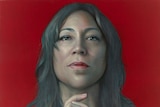 A portrait of Kate Ceberano with her chin slightly raised and hands in front of her chest