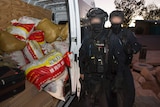 Two AFP officerd with faces blurred next to an open van door containing sacks of drugs.