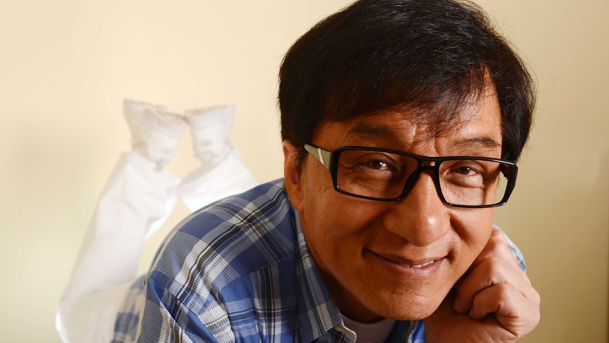 Jackie Chan lying on his stomach with his head rested on one fist