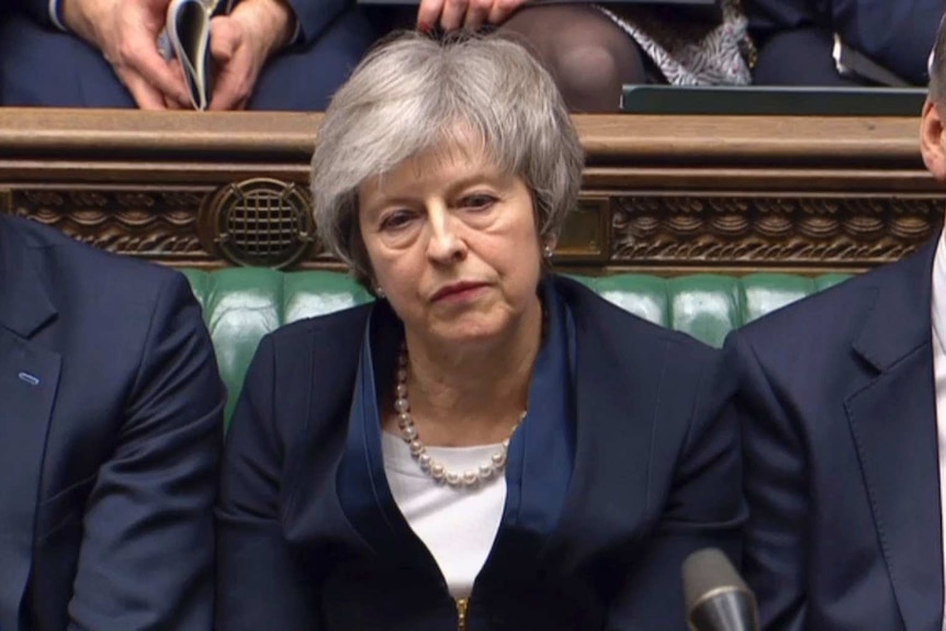 Theresa May sits with a stern face in British Parliament