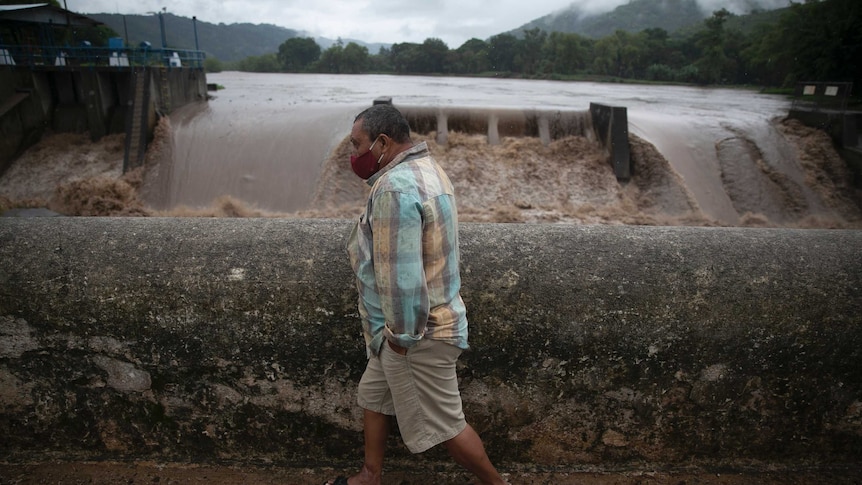 A man walks on a bridge over a river during tropical storm Amanda.