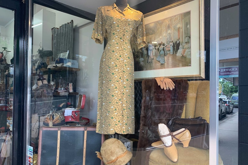 Old style shopfront of vintage shop displaying dresses, hats, gloves, shoes, fur and old suitases