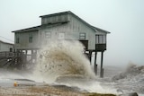 Waves crash onto a house on stilts on a Florida beach