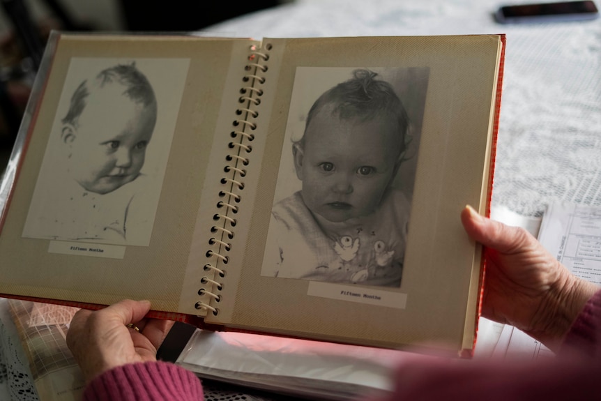 A woman holding a photo album with a child's photos in it.