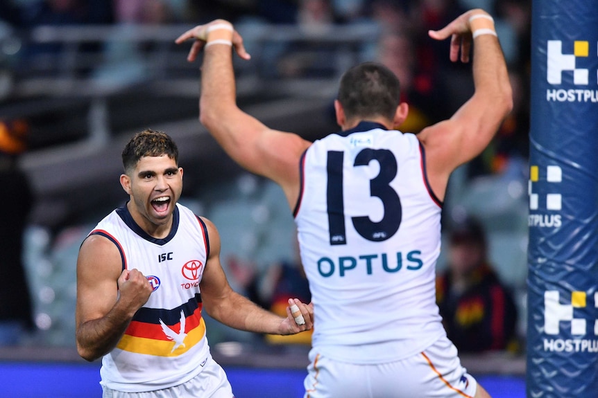 Adelaide Crows players Tyson Stengle pumps his fist after kicking a goal, while teammate Taylor Walker raises both arms.