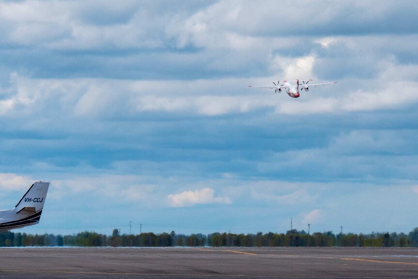 A plane in the air taking off from an airport.