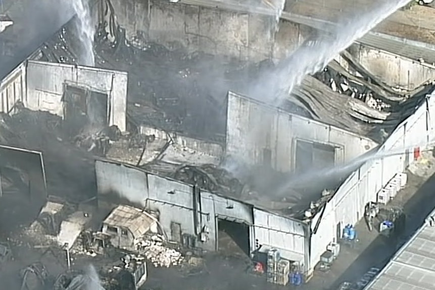 Firefighters douse the blackened remains of the warehouse.