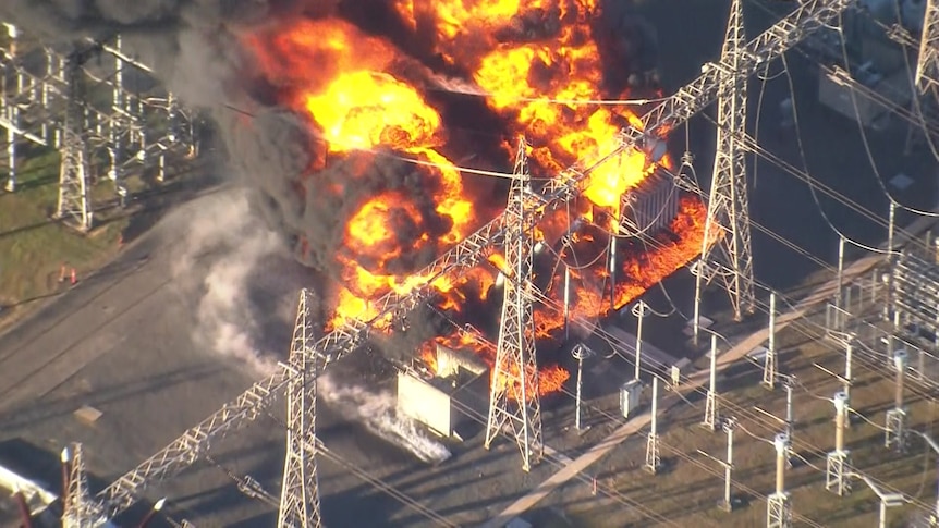 Aerial shot of a big fire burning among poles and wires in a power substation 