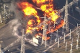 Aerial shot of a big fire burning among poles and wires in a power substation 