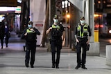 Three protective service officers wearing masks walk down a footpath in Melbourne's CBD.