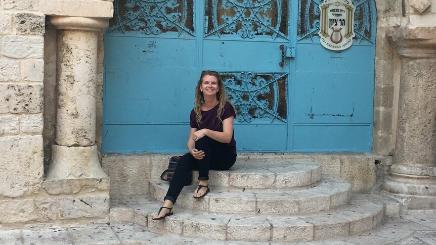 Young woman sitting in front of Jerusalem door, Israel.