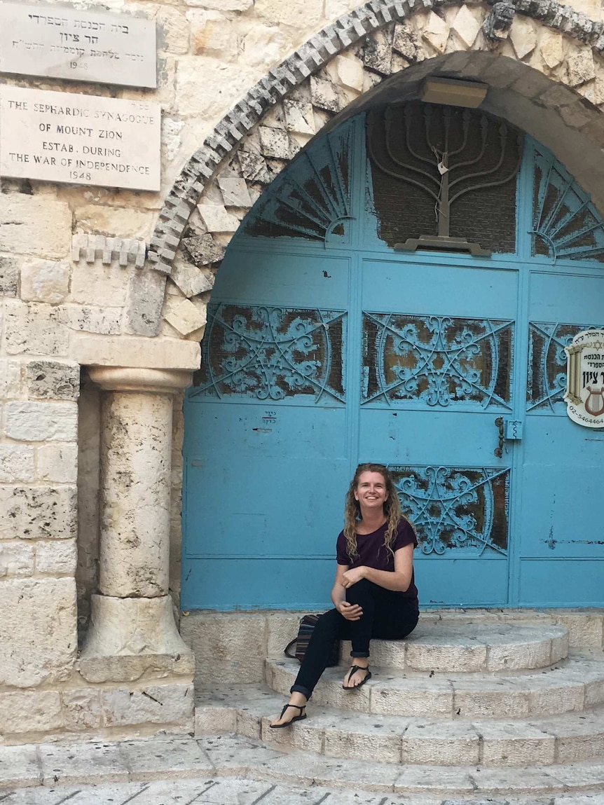 Young woman sitting in front of Jerusalem door, Israel.