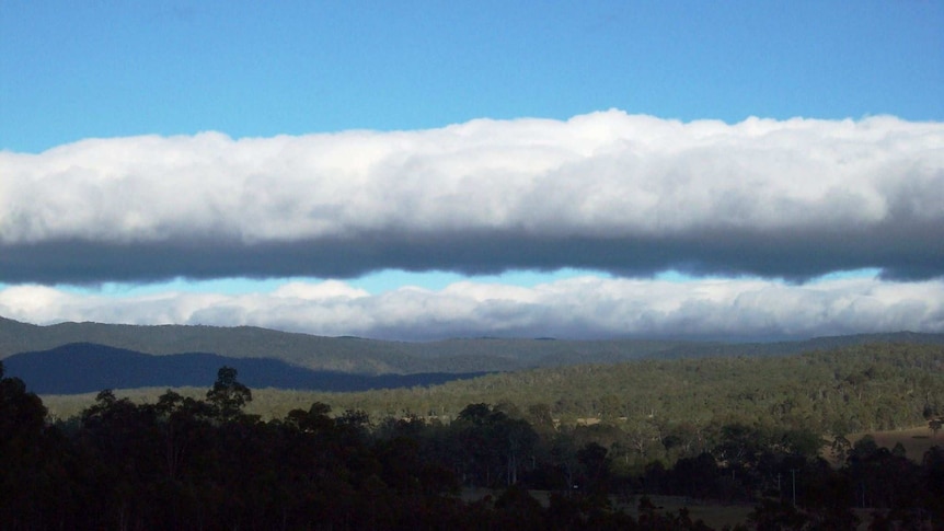 Large white clouds drift over a scenic mountain landscape