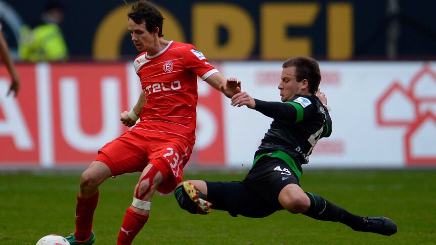 Fortuna Dusseldorf's Robbie Kruse is tackled by a Werder Bremen defender in the German Bundesliga.