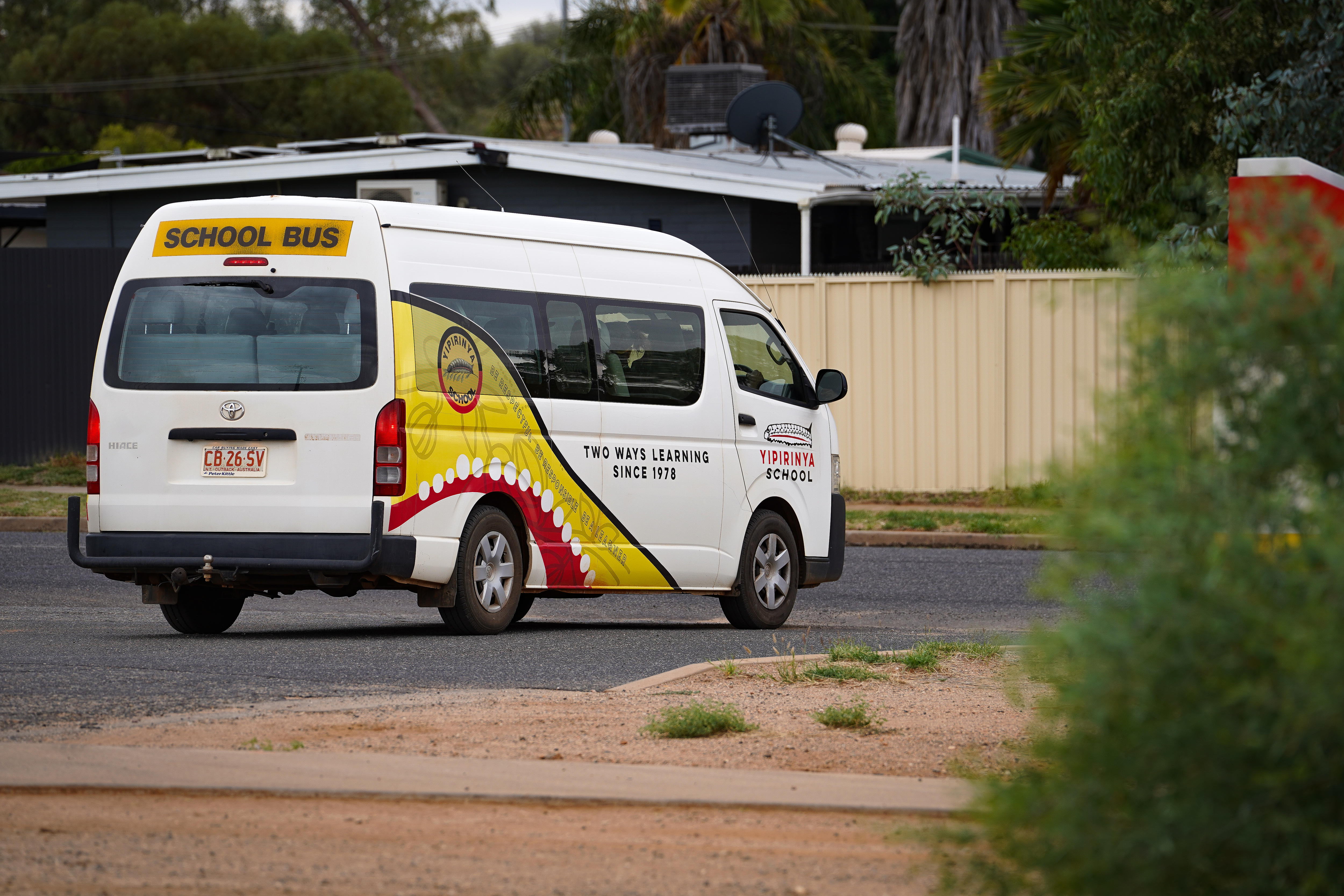 Um ônibus escolar estacionado em frente à escola.
