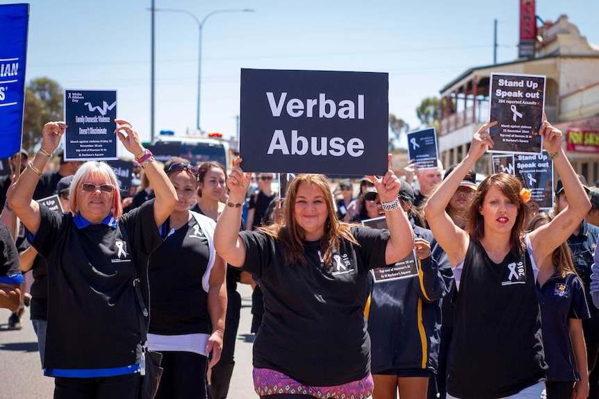 A group of women holding signs and marching in Kalgoorlie on White Ribbon Day.