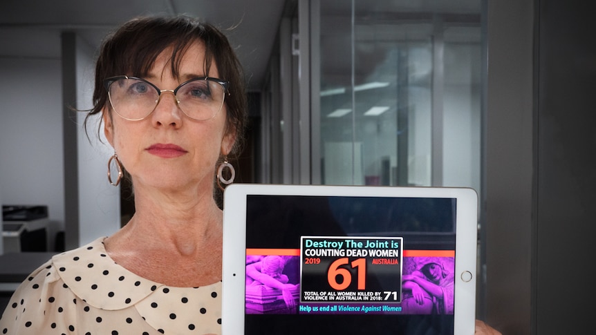 A woman holding an iPad with a graphic on it saying destroy the Joint, counting dead woman, total women killed in 2019 is 61.