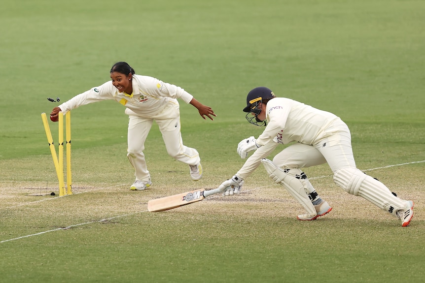 Australia bowler Alana King hits the stumps with the cricket ball in her hand. England batter Anya Shrubsole is caught short.