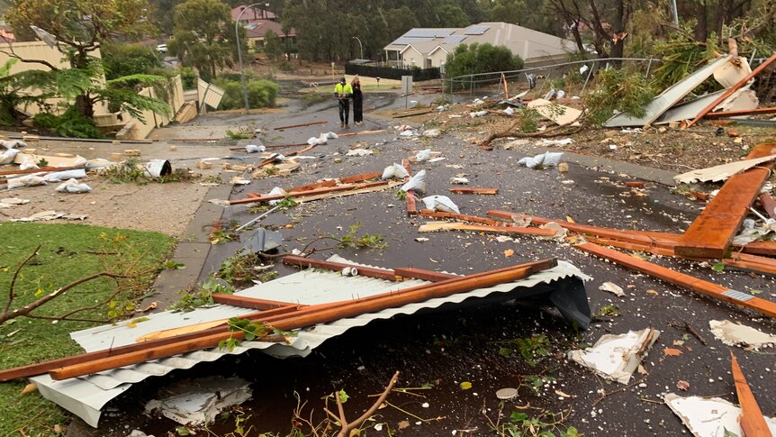 Two people stand in a street surrounded by debris from buildings damaged by a tornado in Bunbury. 
