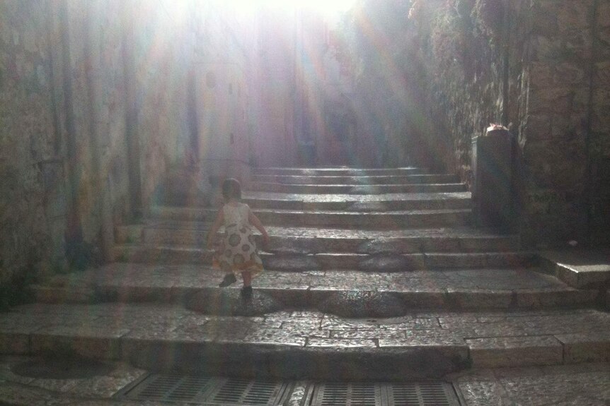 Little girl climbing steps with sun rays shining.