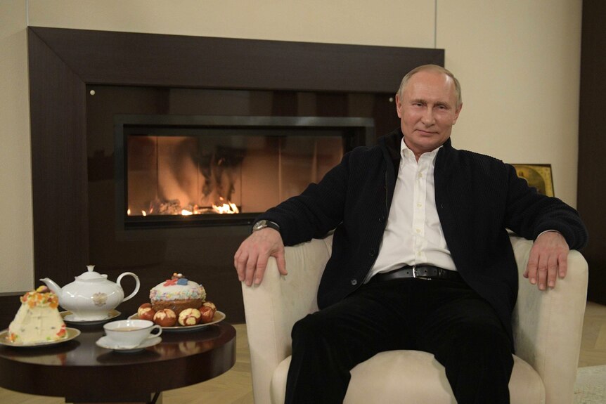 Vladimir Putin se sienta frente al fuego con una taza de té, pastel y huevos de Pascua a su lado.