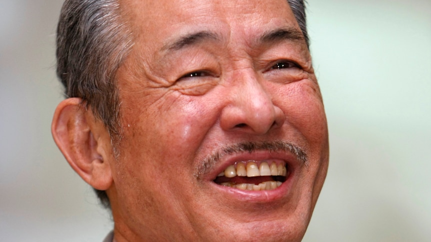 A Japanese man smiles and laughs 