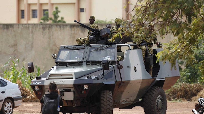 Presidential guard soldiers are seen on an armoured vehicle at Laico hotel in Ouagadougou