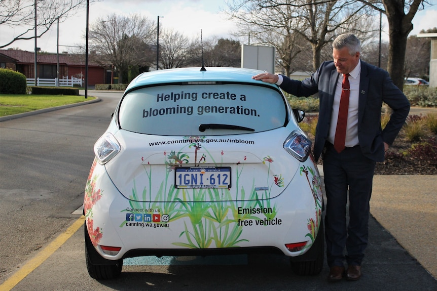 man standing at the side of electric car with colourful design