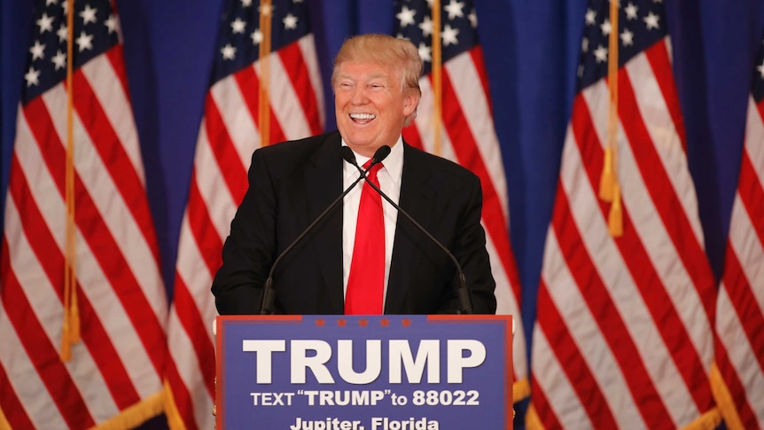 Donald Trump smiles at podium.