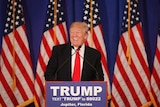 Donald Trump smiles at podium.