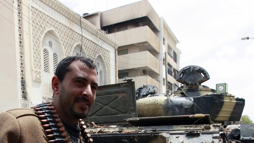 Rebel walks in front of captured tank