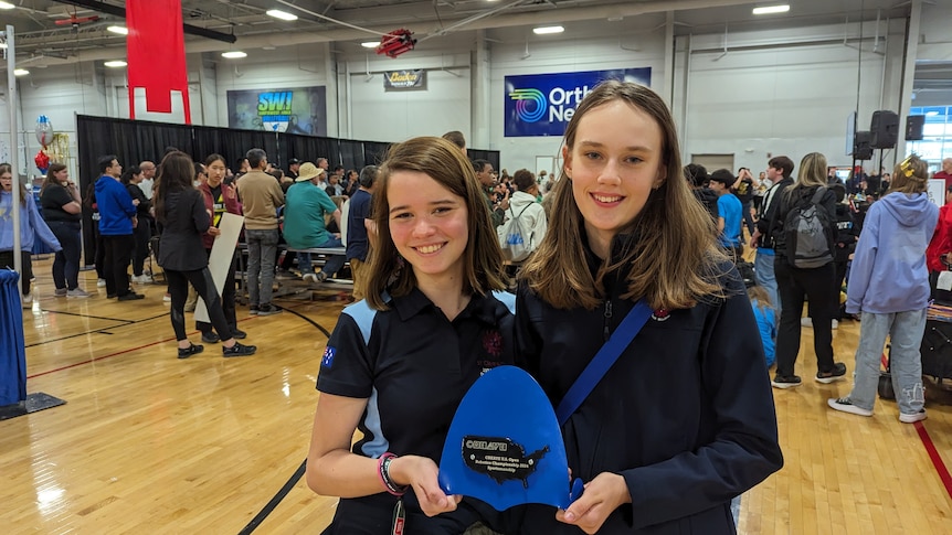 Two girls stand with their award at the World Robotics Championships