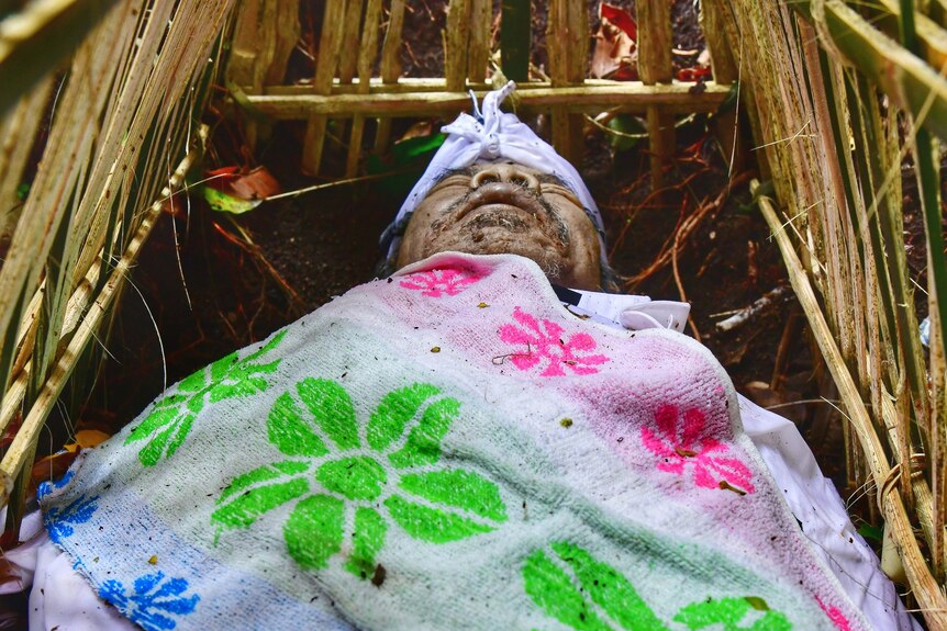 A corpse likes wrapped in a white sheet printed with flowers in a bamboo cage in Trunyan cemetery, Indonesia