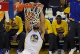 NBA player holds onto the rim of the basket after scoring.