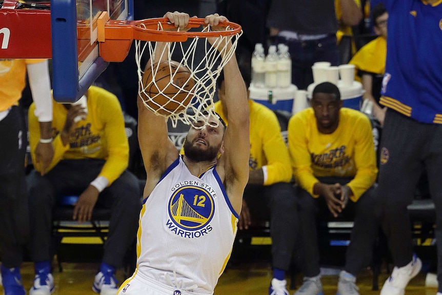 NBA player holds onto the rim of the basket after scoring.