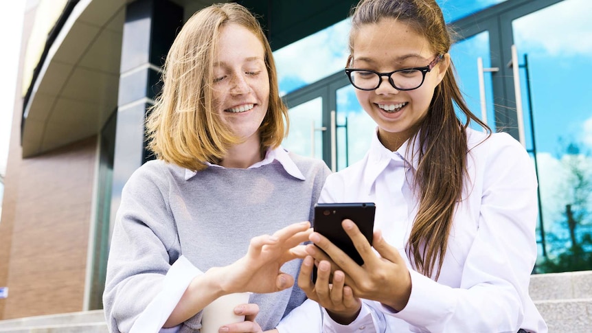Two teenage girls looking at a mobile phone