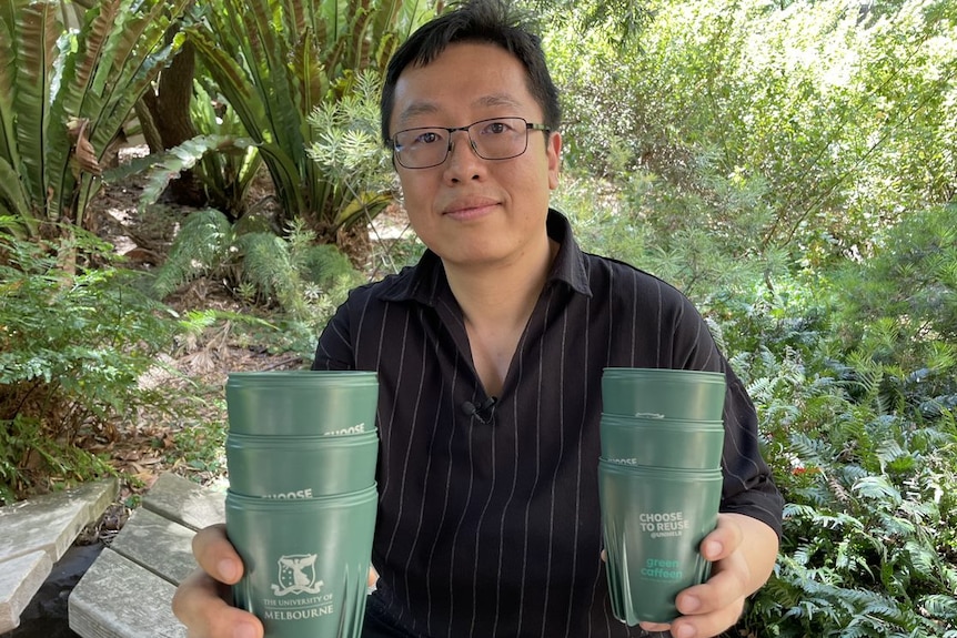 A man holding reusable coffee cups