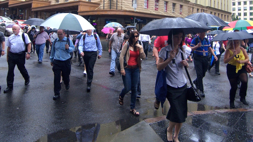 Workers cross a street in the Brisbane CBD during a summer downpour on January 25, 2012.