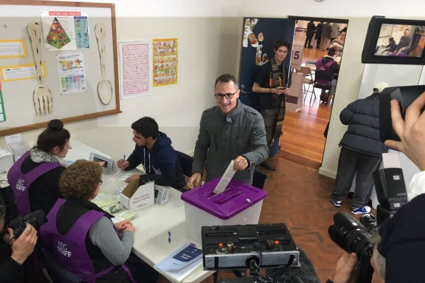 Greens leader puts vote in ballot box surrounded by tv cameras