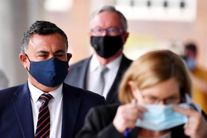 three people at a press conference wearing masks
