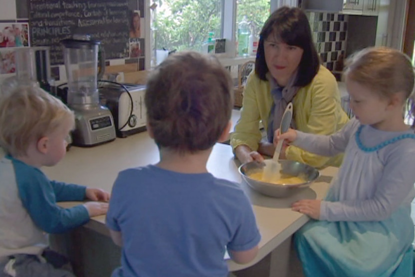 Carer, three kids in a kitchen at family day care